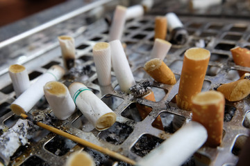 many left smoked cigarette butts fag-end in ashtray on no smoking day.