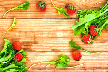Strawberries and salad leaves on desk