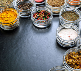 Spices on black background in special jars. Food