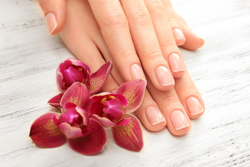 Obraz na płótnie Canvas Woman hands with beautiful manicure and purple orchid on wooden background, close up