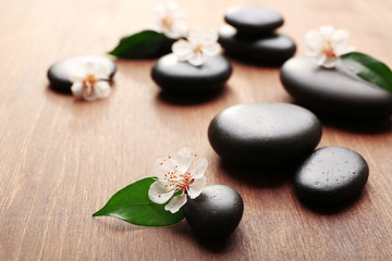 Fototapeta na wymiar Heap of spa hot stones and flowers on wooden background