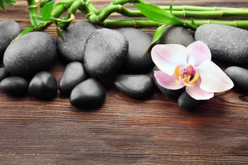 Spa stones and orchid flower on wooden background