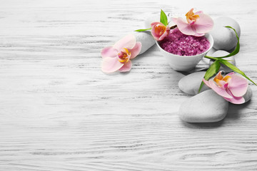 Spa stones, sea salt and orchid flowers on wooden background