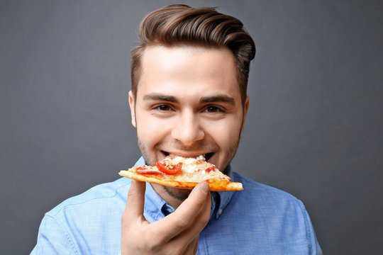 Young Handsome Man Eating Pizza On Dark Background