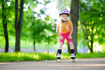 Pretty little girl learning to roller skate  outdoors