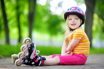 Pretty little girl learning to roller skate  outdoors