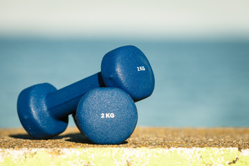 Naklejka na ściany i meble Blue dumbbells sport symbol outdoor on sea shore