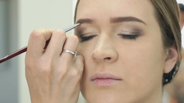 Makeup artist making make-up for stylish model