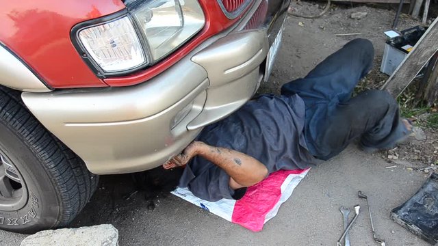 Old man 60 year old thai people professional automotive motor mechanic repair and inspecting the alternator in car at local shop in Nonthaburi, Thailand