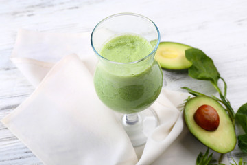 Delicious fresh avocado smoothie on white wooden background