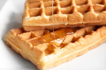 Tasty waffles with honey on plate, closeup