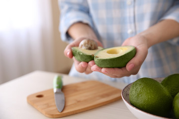 Woman holding fresh avocado in kitchen © Africa Studio