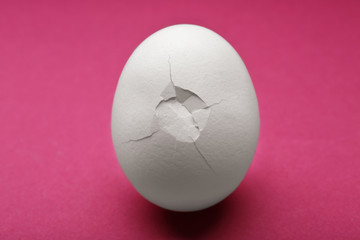 Cracked egg on pink background