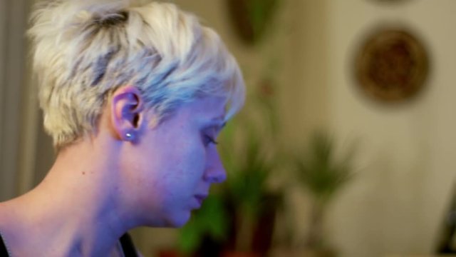 Young, Blond Haired Woman Removing Her Bra
