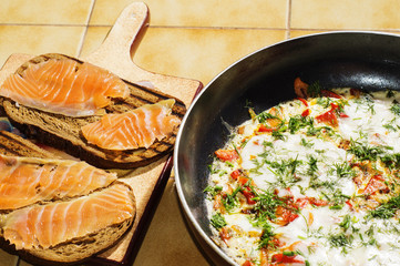 Omelet with tomatoes, cheese and dill and sandwiches with salmon