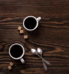 Two cups of espresso with pieces of cane sugar  on wooden table.