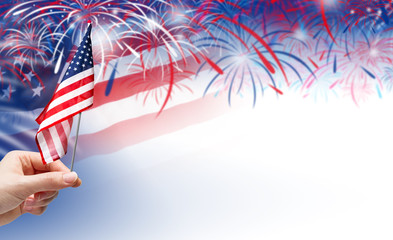 Hand holding USA flag on fireworks background