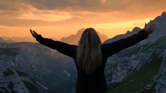 young woman raising arms  on top of a mountain sign of happiness success concept