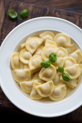 Close-up of a glass plate with ravioli in bouillon, top view