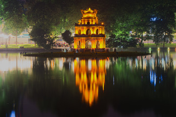 Fototapeta premium Ancient Temple of Turtles on the background of the waterfront Hoan Kiem lake in the night illumination. Hanoi, Vietnam