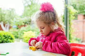 Little blonde girl making creative exercise at Easter