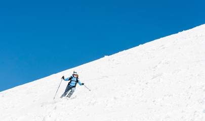 Female skier tackling a steep slope.