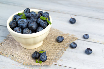 Beautiful fresh blueberries in a white ceramic bowl on a wooden table