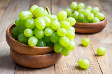 Bunch of green ripe grapes in a wooden bowl