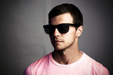 Dark portrait of a young man in sunglasses, social isolation and anonymity concept