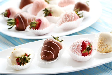 Strawberries covered in chocolate on a blue wooden table