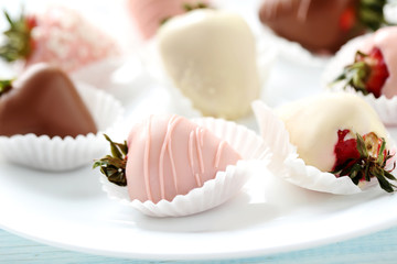Strawberries covered in chocolate on a blue wooden table