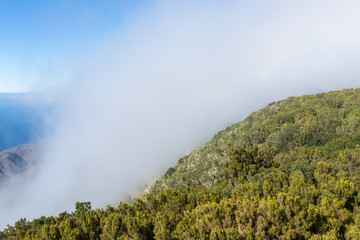 Overlook from the Mirador de Alojera to the canyon Barranco del Mono with the village Alojera. Trade winds with huge clouds comes from the north into the valley. The clouds comes from the Azores
