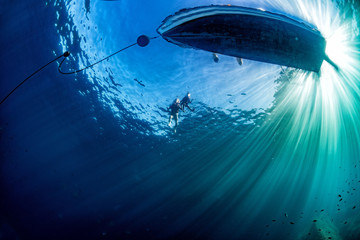 boat ship from underwater blue ocean with sun rays