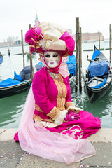 Fototapeta na wymiar Pink dressed woman and gondolas at Venice carnival