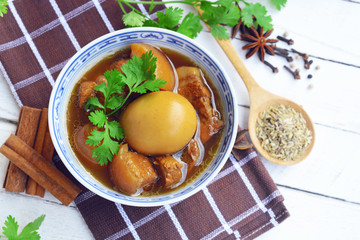 eggs and pork in brown sauce. three layer pork with eggs in sweet gravy sauce. braised pork belly and chicken eggs in soy sauce with five spice background. thai food.