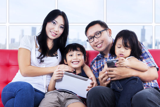 Happy Family On Red Sofa At Apartment