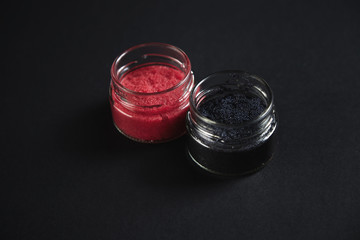 Two transparent jars with red and black lumpfish caviar isolated on black, luxury serving set