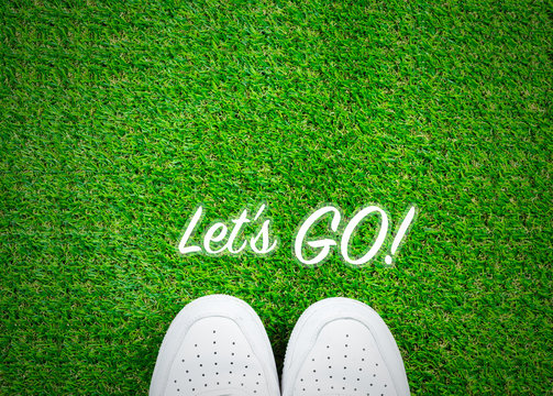 Let's go text on grass flat lay with shoes; travel concept