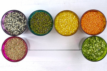 Multicolored clear glasses with various legumes ( green peas, re