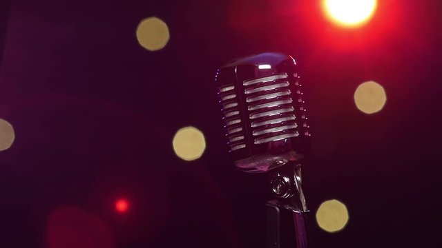 Vintage microphone against dark blurry background with bright flashing lights
