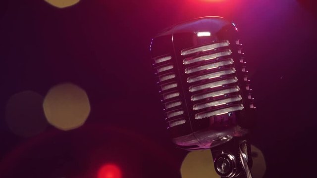 Vintage microphone against dark blurry background with bright flashing lights