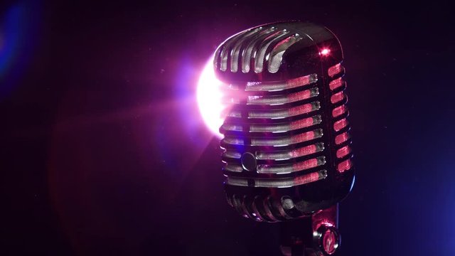 Classic microphone slow rotating on background lamp stroboscope in dark