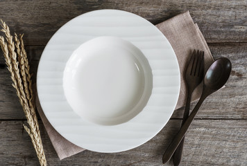 Empty dish with spoon and fork on old wooden background