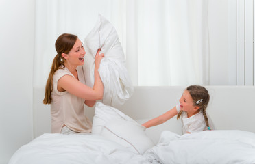 Obraz premium Mutter und Tochter bei Kissenschlacht auf dem Bett