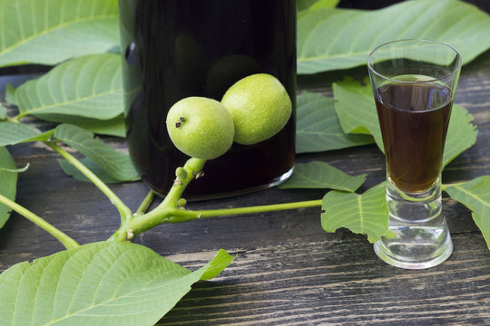 Liqueur with green walnuts on a dark wooden background