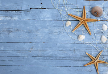 Maritime Dekoration auf blauem Holzhintergrund mit Holzschiff, Seestern, Muscheln, Treibholz ud...