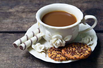Сoffee with milk in vintage porcelain cup,vegan cookies and crisp waffles on old wooden background close up. Selective focus. 