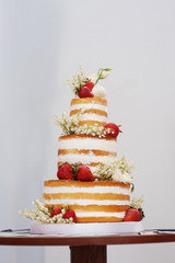 three-tiered wedding cake with strawberries on table