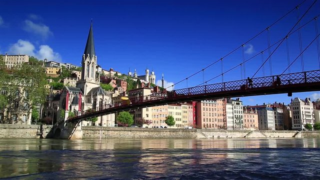 People are walking over the Passerelle Saint-Georges bridge over Rhone river in Lyon, France.