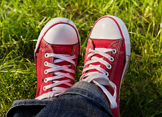 Feet in dirty red sneakers outdoors.